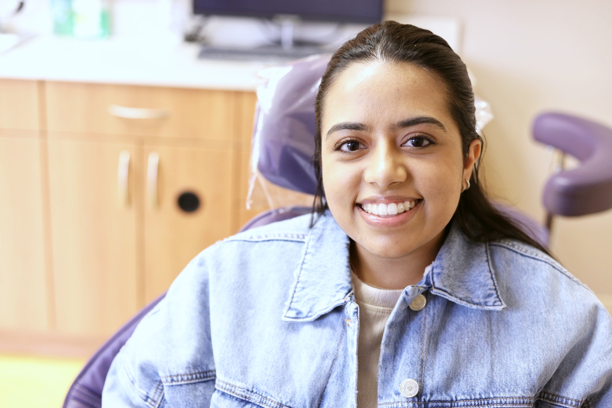 Smiling patient in dental chair at Monroe Orthodontics, showcasing comfort and satisfaction with Invisalign treatment in South Brunswick.